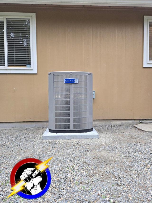 An American Standard heat pump condenser standing on a pad beside a house