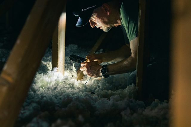 A worker up in an attic, in among the insulation