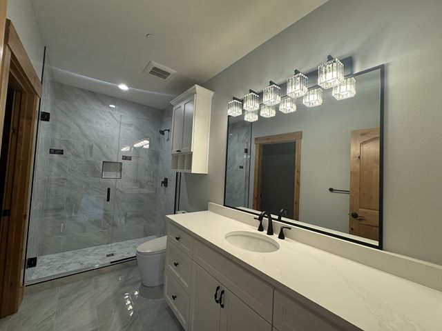 A bathroom vanity with a lit mirror above it