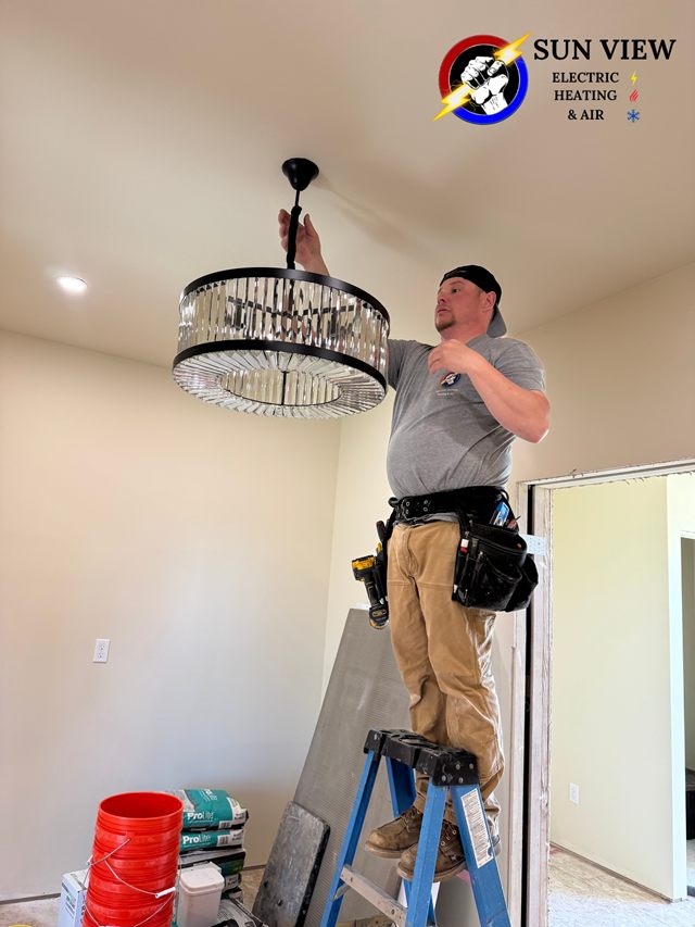 A technician on a ladder fitting a chandelier