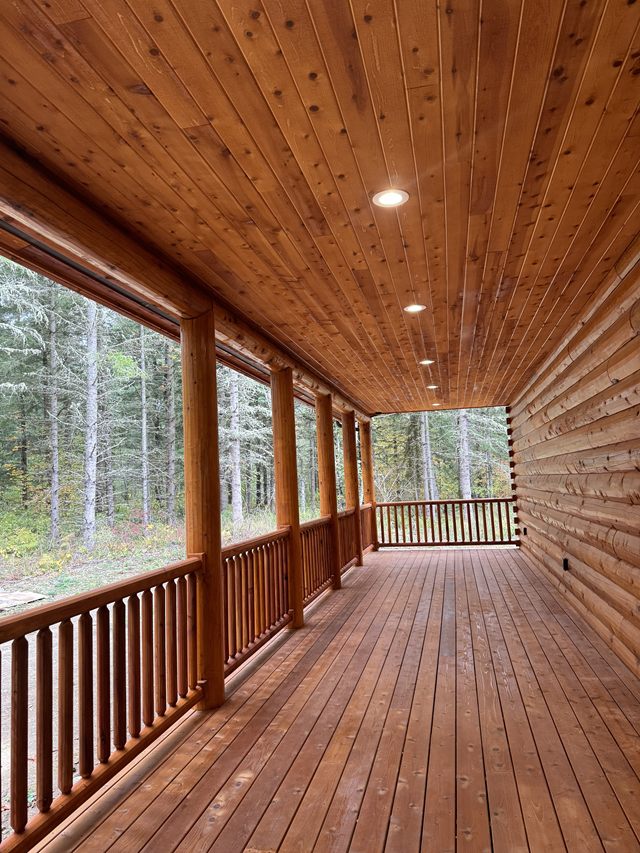 A long covered porch on a log home with the soffits lit