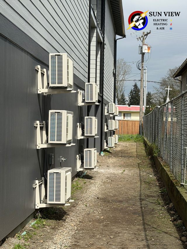 A row of ductless outdoor units mounted on wall brackets down the side of a building