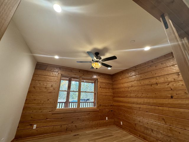 A log-walled room with a ceiling fan and recessed ceiling lights